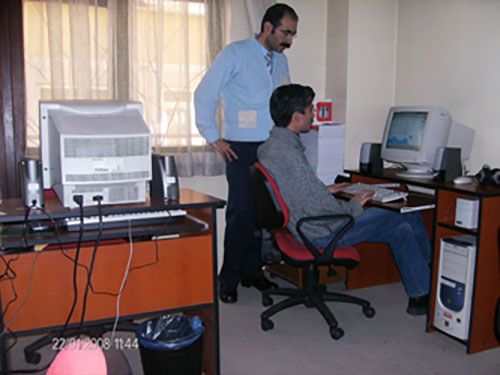 Bilgisayar odasında bir öretmen ve öğrenci bilgisayar başındalar